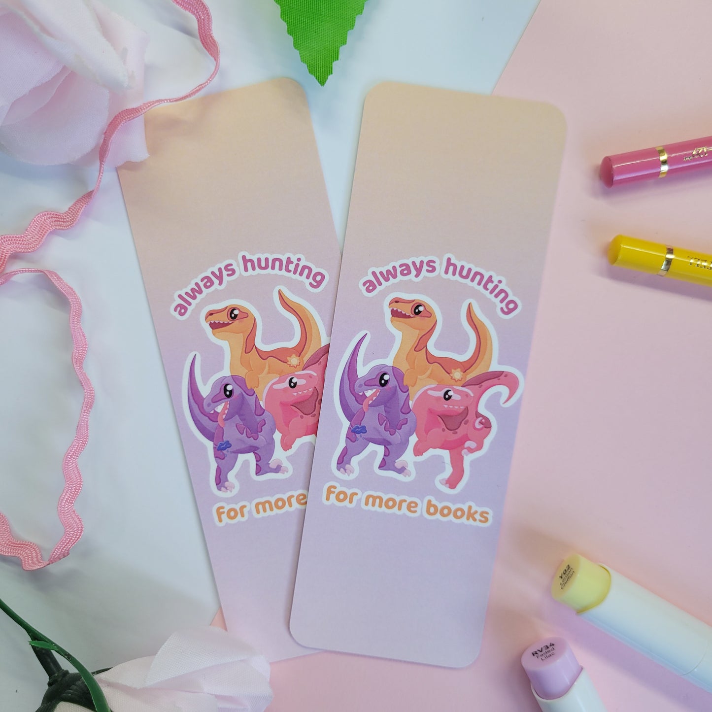 Pack of velociraptors on a bookmark with the text "always hunting for more books"