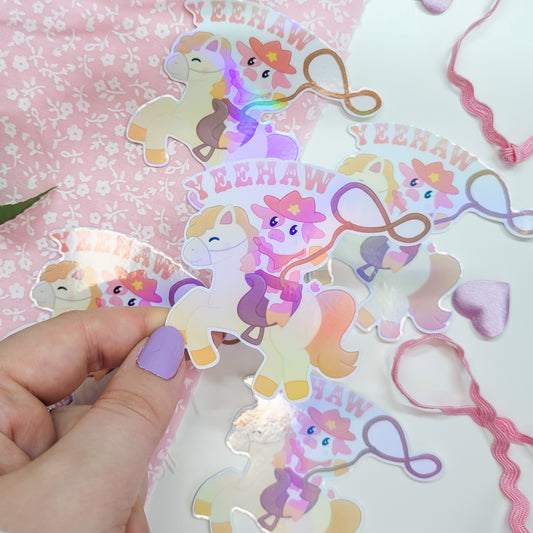 Cute cowboy sticker featuring a cow riding a horse with a lasso saying Yeehaw!