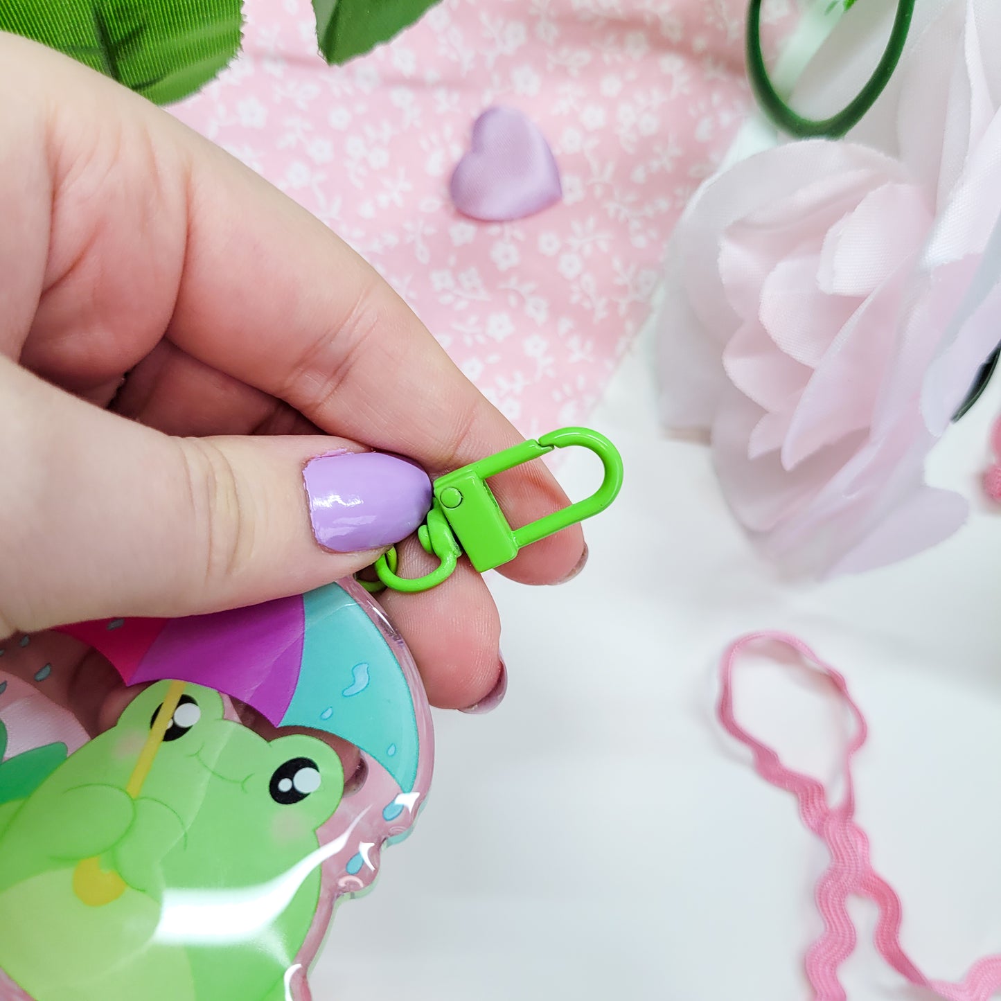 Cute Frog with an umbrella in the rain on an acryllic keychain, features a green clasp and double sided design with epoxy on the front