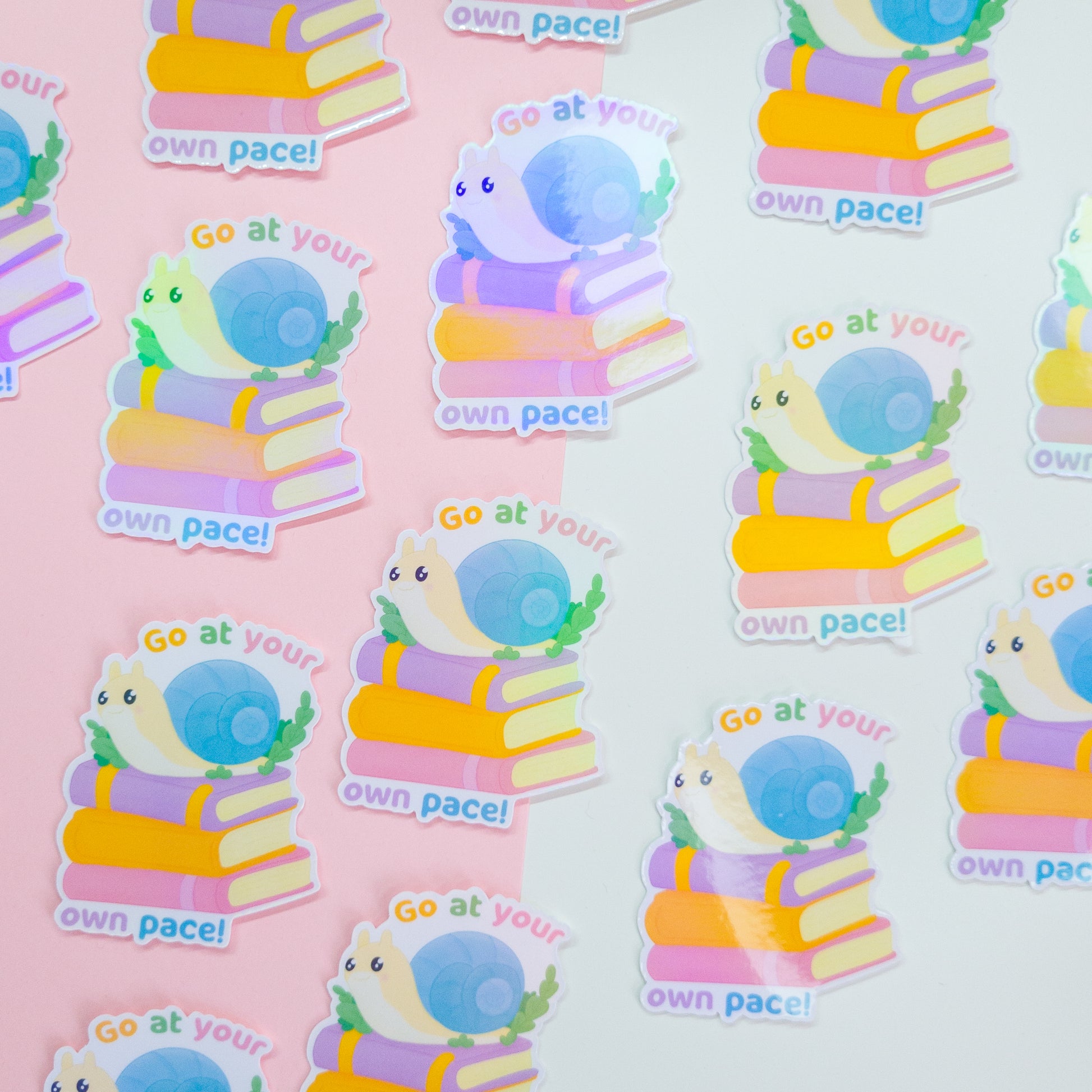 cute bookish sticker, featuring a cute snail on a stack of books and the text 'go at your own pace'