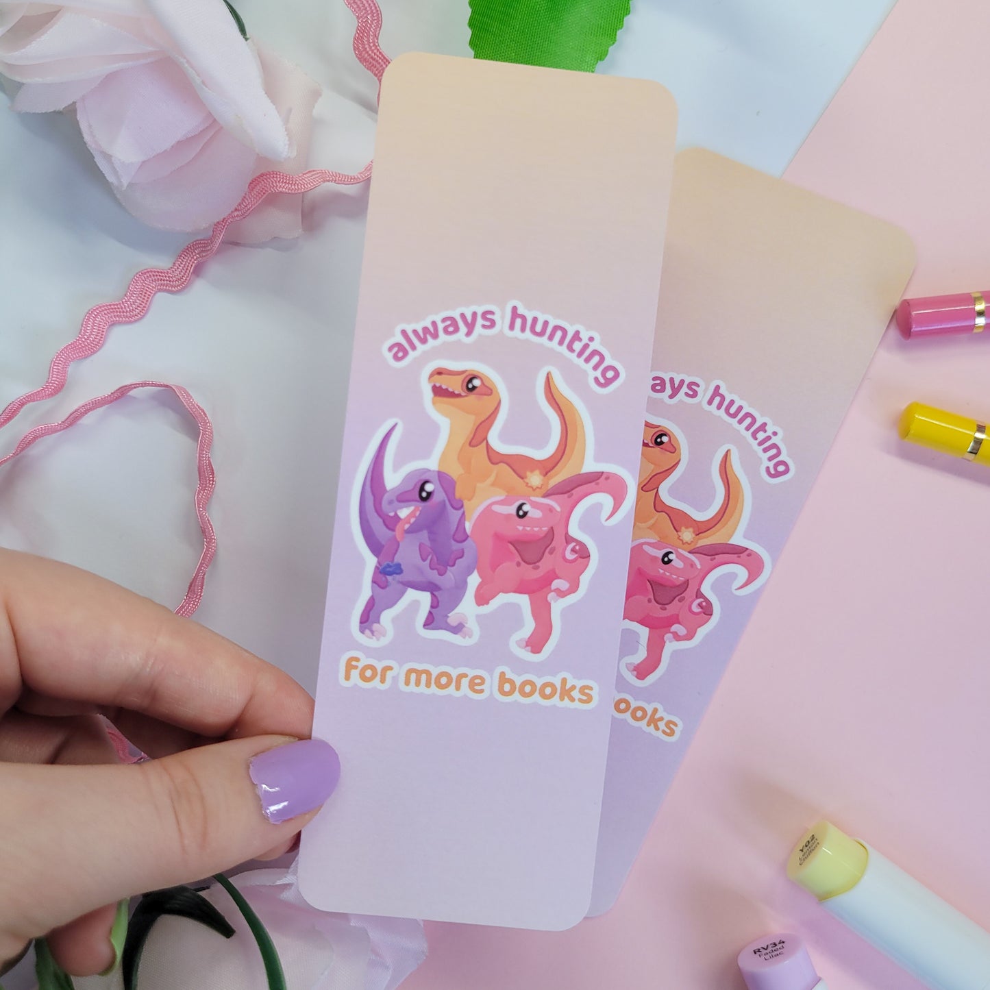 Pack of velociraptors on a bookmark with the text "always hunting for more books"