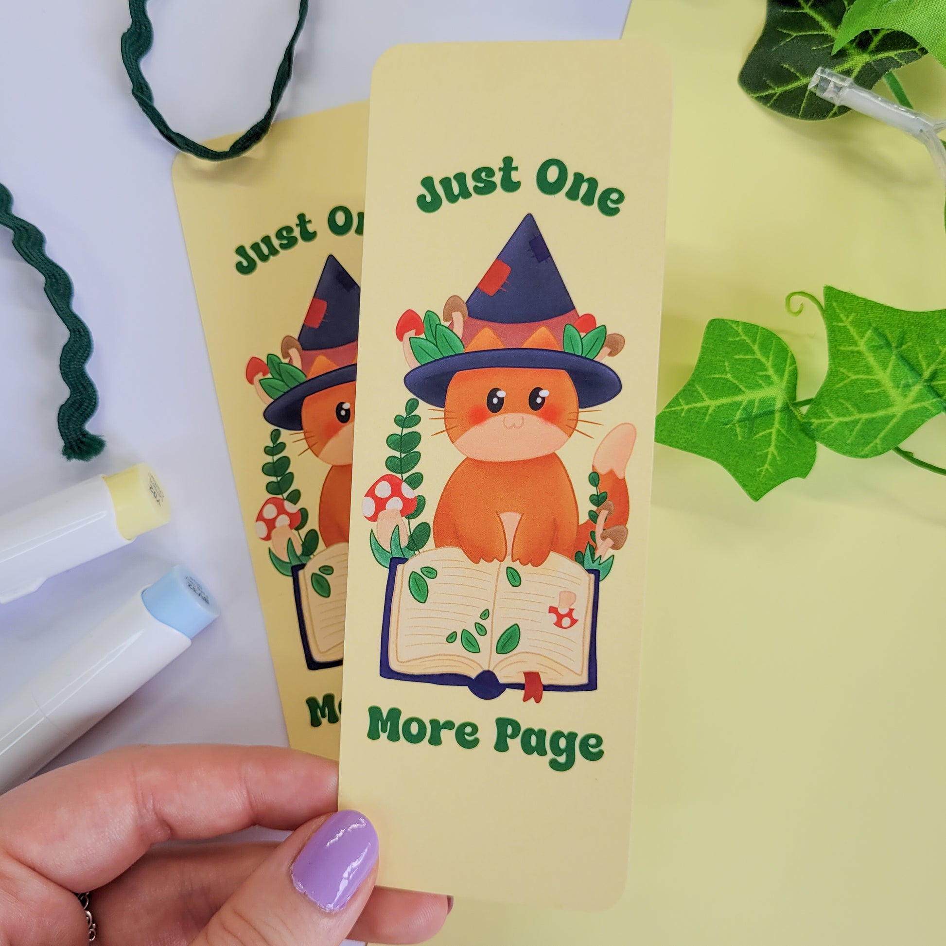 Cute cat witch bookmark featuring the text "Just one more page"