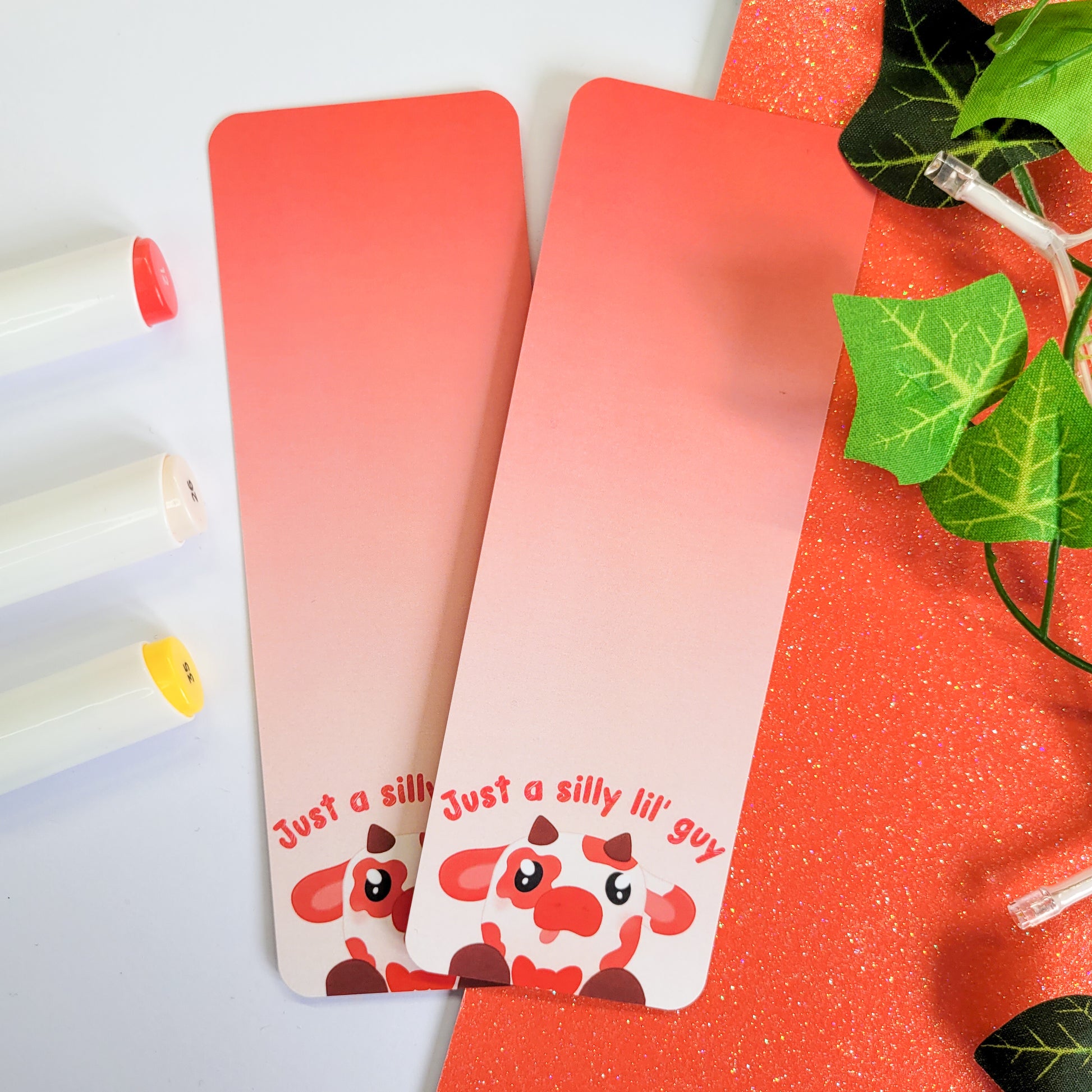 Silly red cow with his tongue out on a bookmark with the text "just a silly lil' guy"