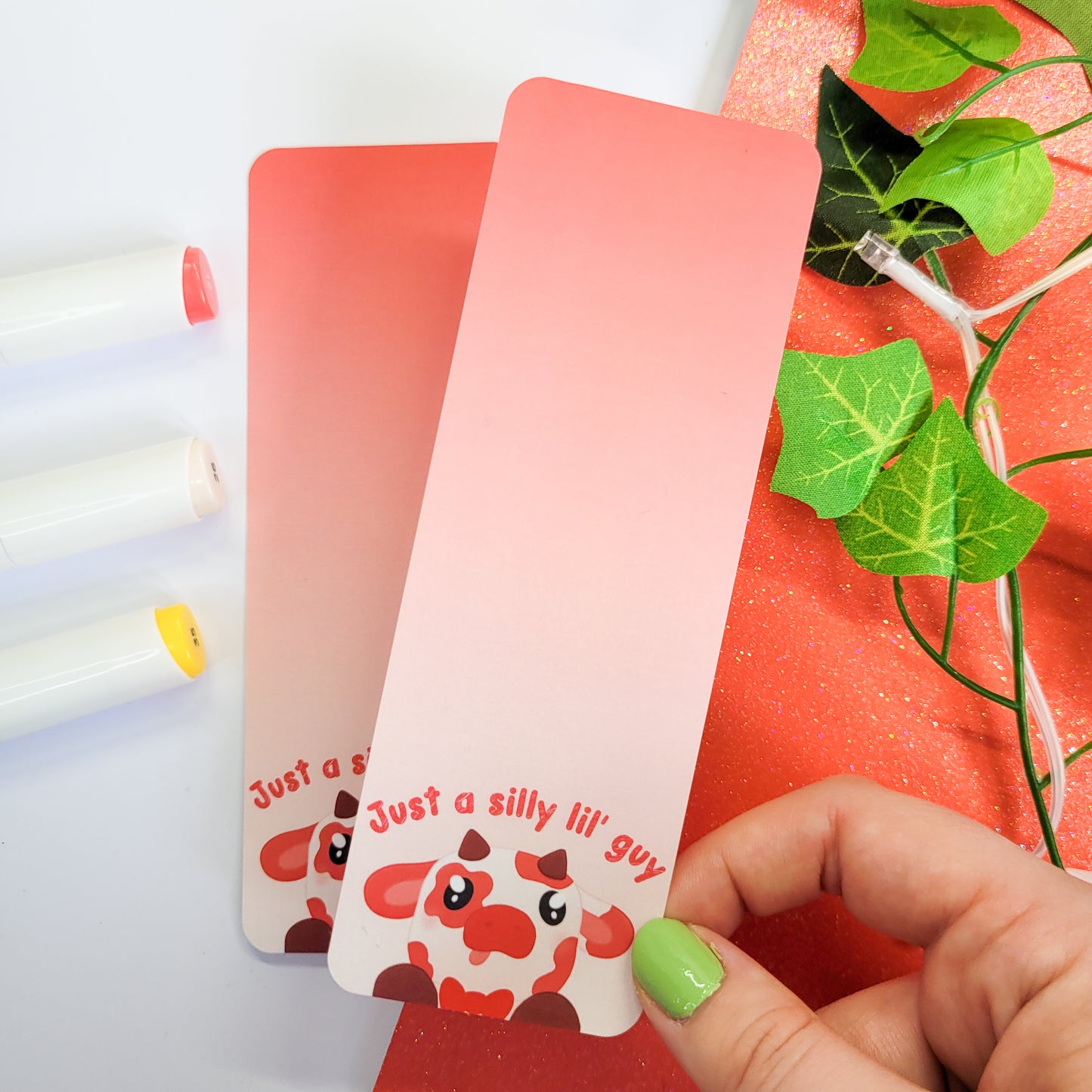 Silly red cow with his tongue out on a bookmark with the text "just a silly lil' guy"