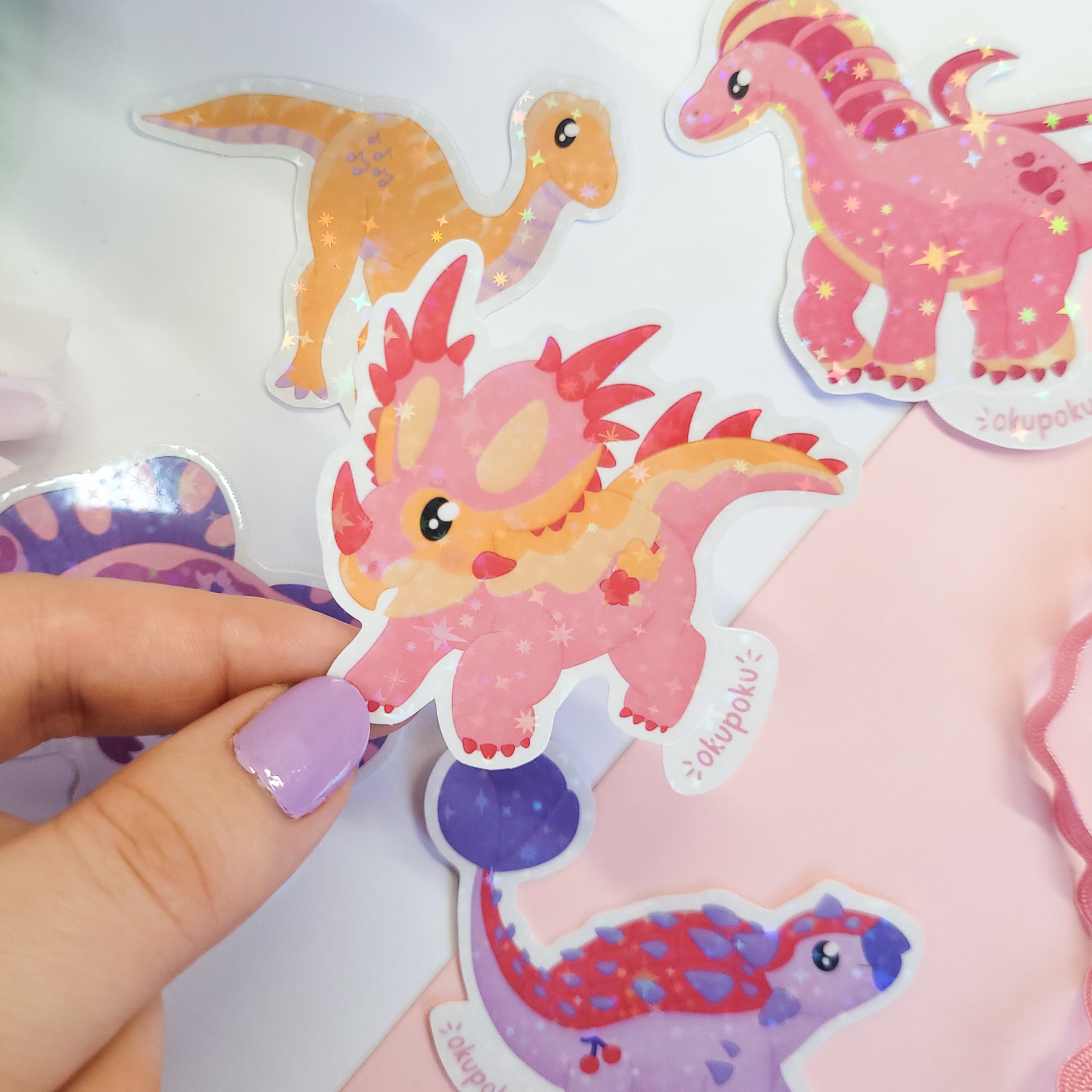 Colorful dinosaur stickers with a hand holding one of them.