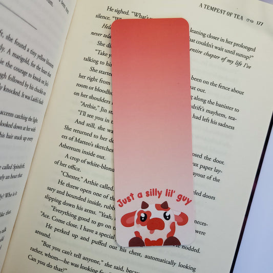 Silly red cow with his tongue out on a bookmark with the text "just a silly lil' guy"