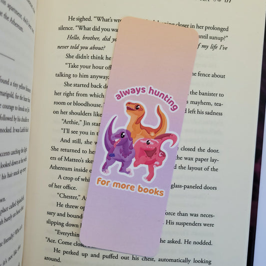 Pack of velociraptors on a bookmark with the text "always hunting for more books"