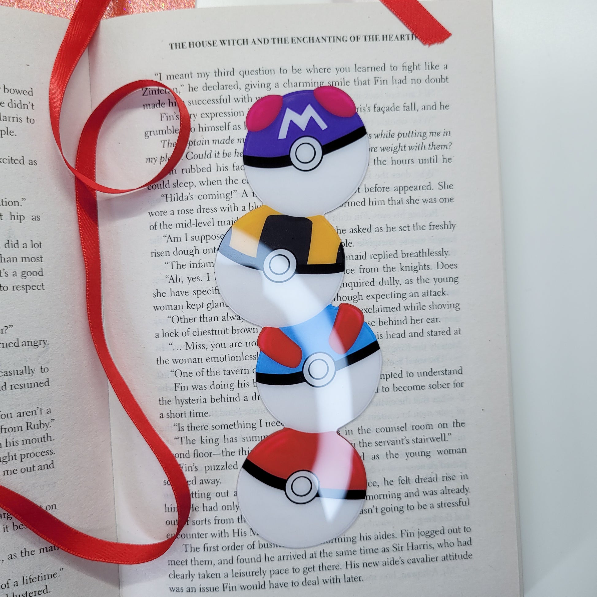 Cute bookmark in the shape of 4 stacked pokeballs shown in use
