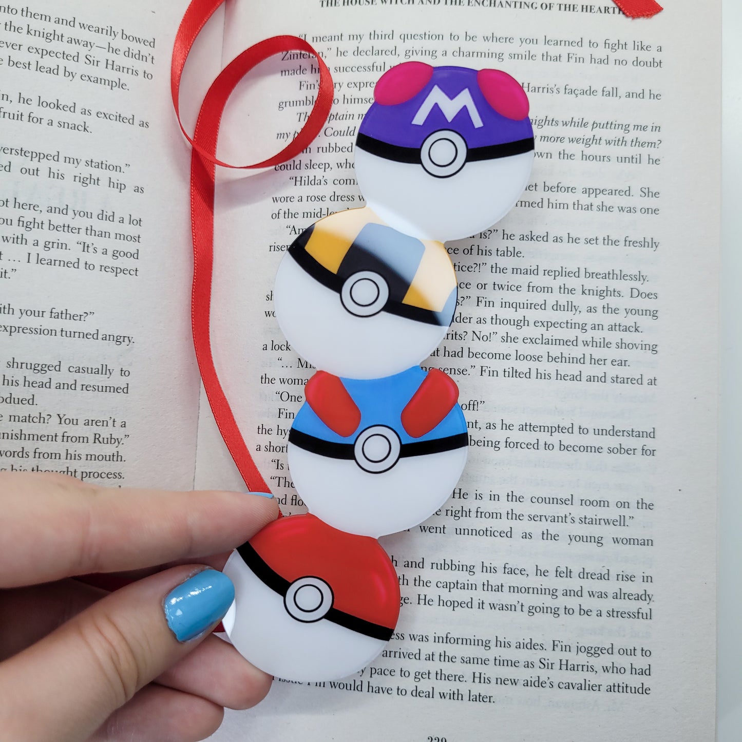 Cute bookmark in the shape of 4 stacked pokeballs shown in use