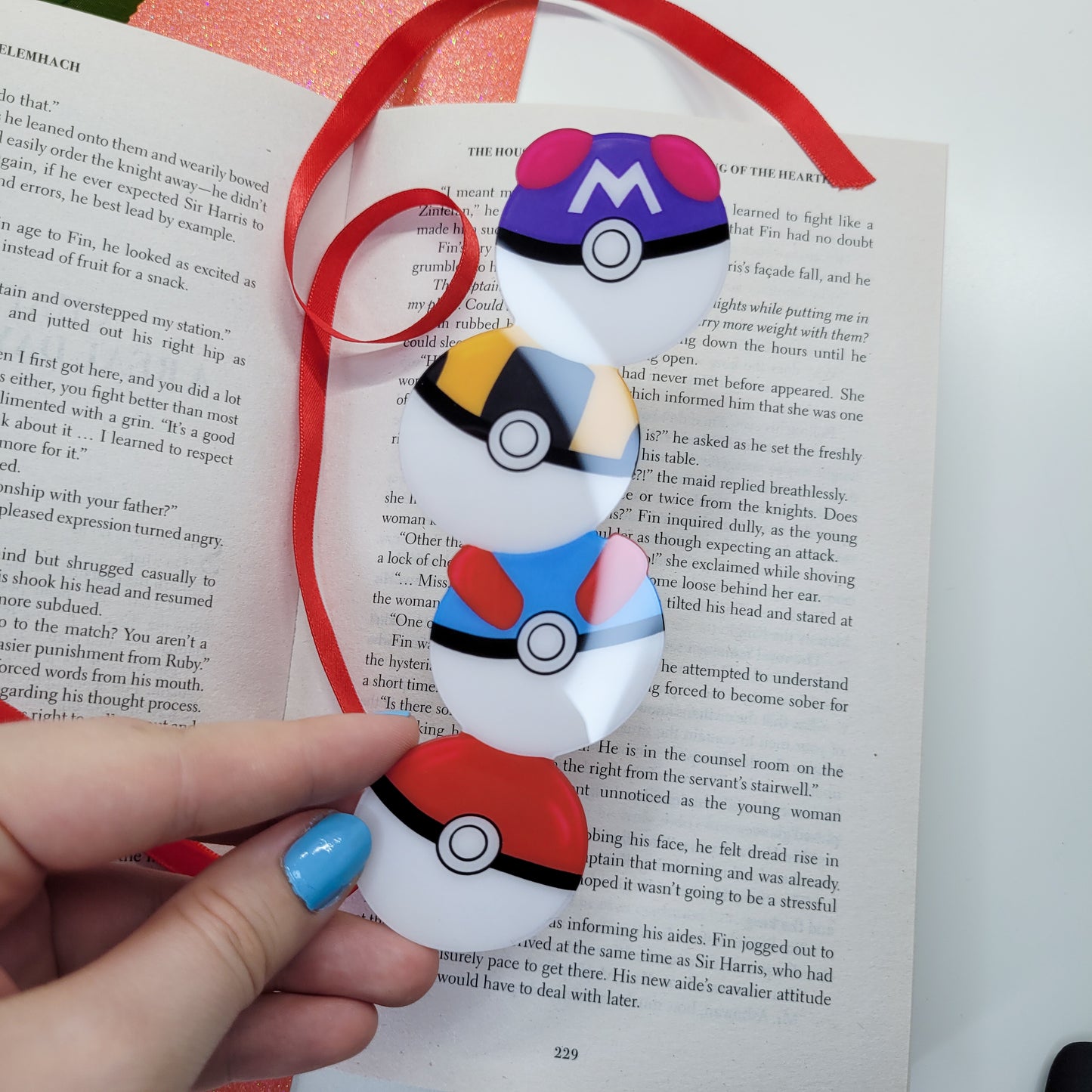 Cute bookmark in the shape of 4 stacked pokeballs shown in use