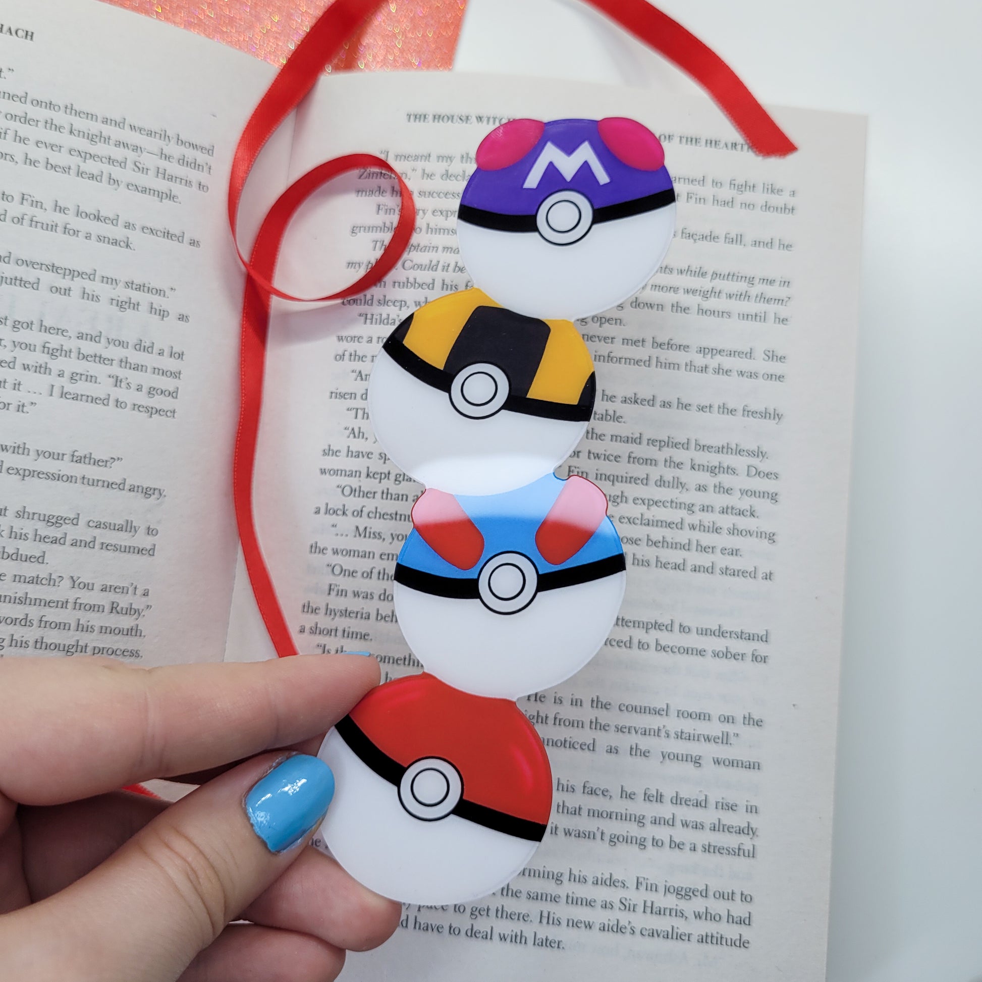 Cute bookmark in the shape of 4 stacked pokeballs shown in use