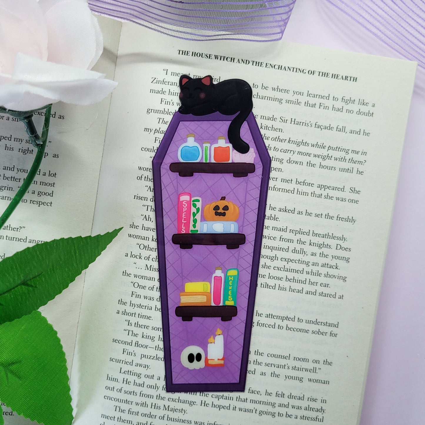 Gothic purple and black bookshelf with a black cat sat on top
