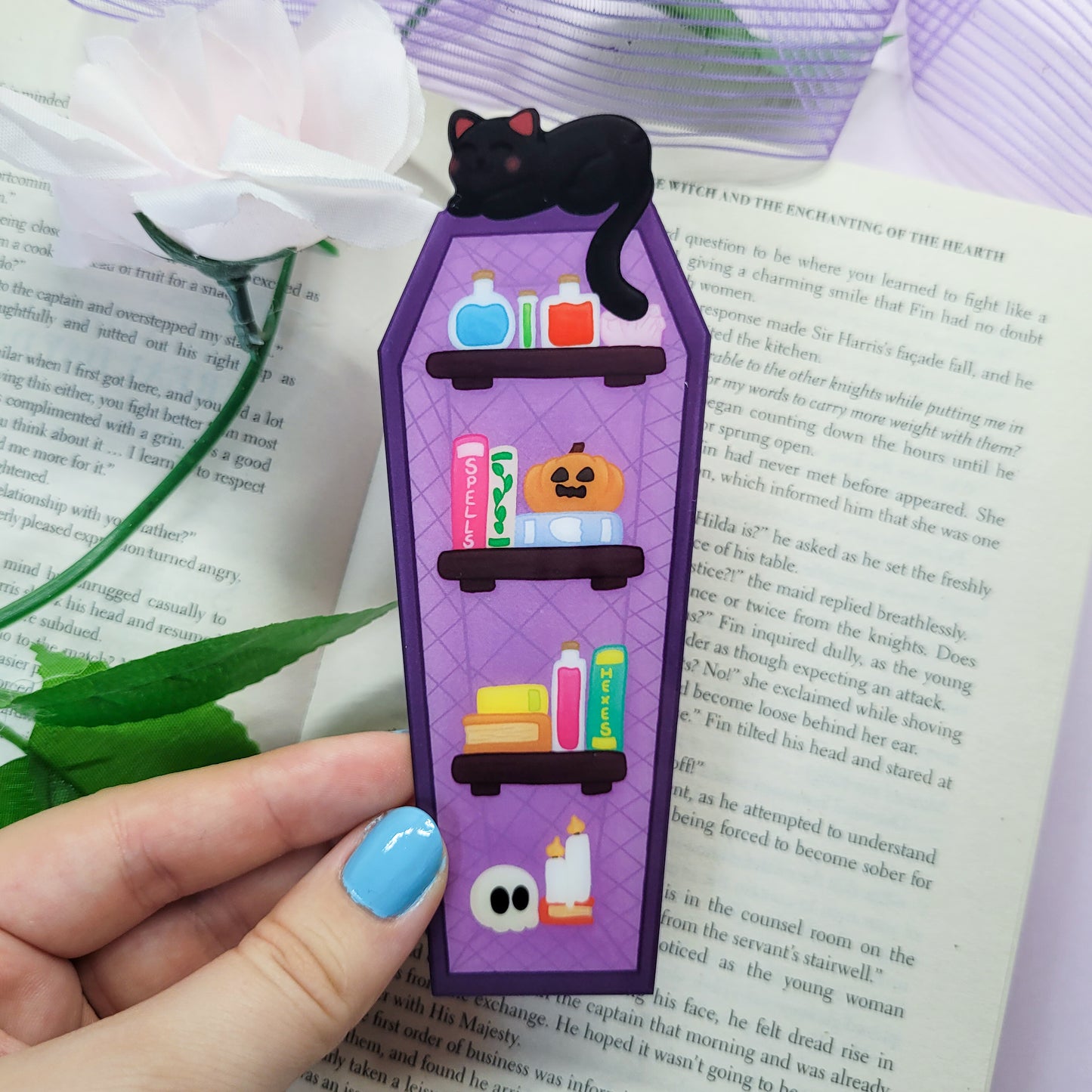 Gothic purple and black bookshelf with a black cat sat on top